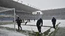 Pekerja staf membersihkan salju dari lapangan sebelum pertandingan antara Burnley dan Tottenham Hotspur di Turf Moor, Inggris, Minggu (28/11/2021). Baik pihak Burnley maupun Tottenham menerima keputusan ini. Mengenai tanggal pengganti, hal itu diputuskan di lain hari. . (AP Photo/Rui Vieira)