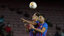 Gelandang Barcelona, Gavi dan Sergio Busquets melompat untuk menyundul saat menjamu Granada pada lanjutan La Liga di Camp Nou, Selasa (21/9/2021) dini hari WIB. Barcelona dipaksa bermain imbang 1-1 oleh tamunya Granada. (AP Photo/Joan Monfort)