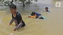 Anak-anak melintasi banjir di Desa Sukalaksana Kabupaten Bekasi, Jawa Barat, Senin (22/02/2021). Ketinggian air di sekitar permukiman warga mencapai 1,5 meter. (Liputan6.com/Herman Zakharia)