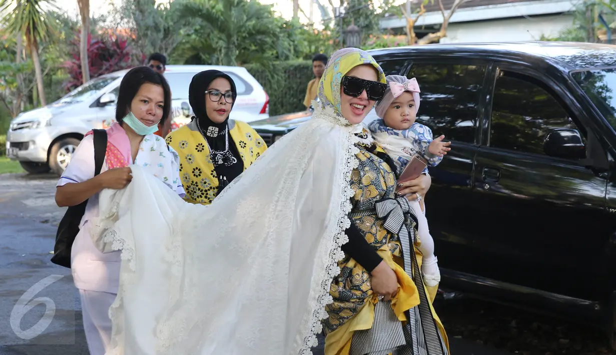Penyanyi Syahrini menggendong keponakan usai melaksanakan salat Idul Adha 1437 H di taman Tanah Sereal, Bogor, Senin (12/9). Syahrini memakai baju muslim bermotif, dilengkapi dengan luaran warna putih plus kacamata hitam. (Liputan6.com/Herman Zakharia)