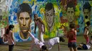 Seorang pelatih sedang memperhatikan anak didiknya melakukan gerakan Capoeira di dekat tembok lukisan wajah pemain top dunia, Brasil, Rabu (21/05/2014) (AFP PHOTO/Yasuyoshi CHIBA).