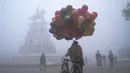 Seorang penjual balon berjalan di sepanjang jalan Heritage di tengah kabut tebal di hari yang dingin di Hari Tahun Baru, di Amritsar (1/1/2021). Gelombang Dingin, Kabut Tebal Mencengkeram India Utara di Hari Tahun Baru di Delhi. (AFP/Narinder Nanu)