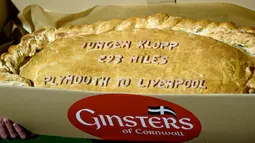 Sindiran pada Jurgen Klopp berupa kue pastel raksasa yang bertuliskan jarak tempuh Liverpool menuju Plymouth. (EPA/Gerry Penny)