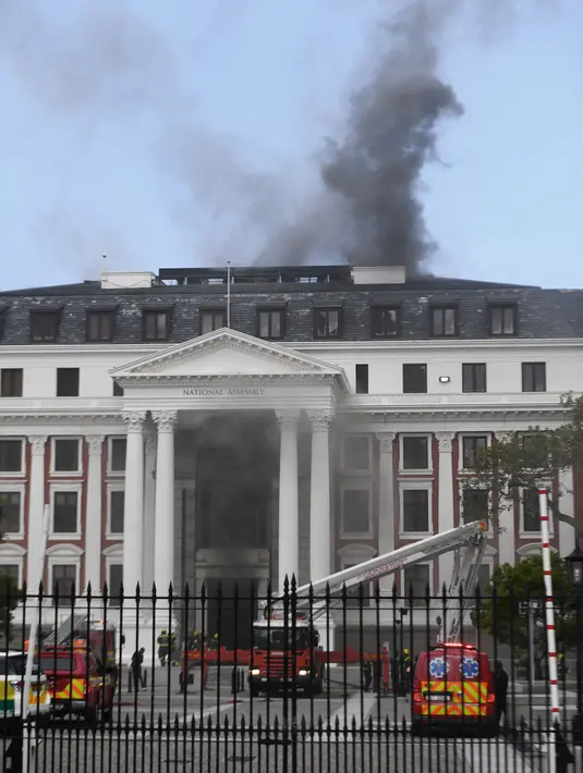 Asap mengepul dari atap sebuah gedung selama insiden kebakaran di kawasan Parlemen Afrika Selatan di Cape Town (2/2/2022). Kebakaran terjadi tepat sehari setelah pemakaman aktivis pemenang Nobel Perdamaian, Desmond Tutu. (AFP/RODGER BOSCH)