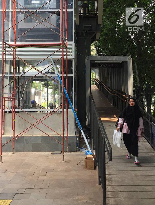 Pejalan kaki melintas di dekat pembangunan lift pada jembatan penyeberangan orang di Jakarta, Senin (13/5). Pembangunan lift pada tiga JPO yang berada di Jalan Sudirman itu bertujuan meningkatkan kenyamanan kepada warga dan ditargetkan rampung akhir bulan ini.(Liputan6.com/Immanuel Antonius)