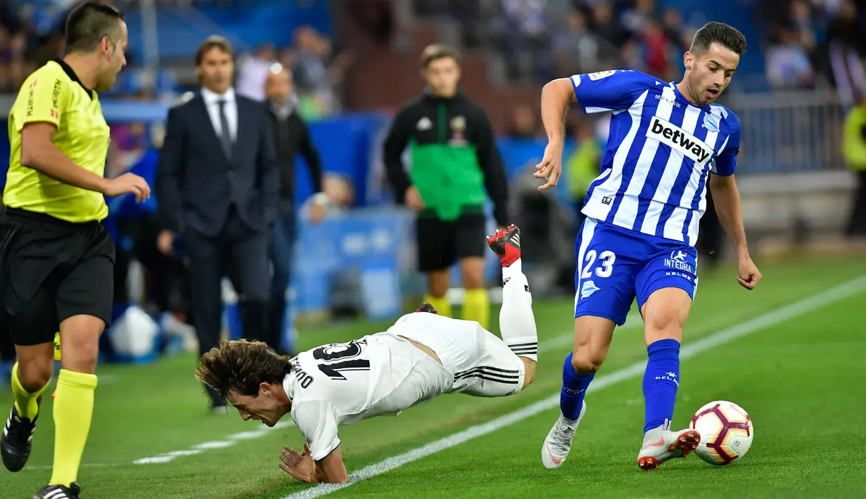 Pemain Real Madrid, Alvaro Odriozola terjatuh saat mengejar bola yang dibawa pemain Deportivo Alaves Jony Rodriguez saat bertanding pada lanjutan La Liga Spanyol di stadion Mendizorroza, Vitoria (6/10). (AP Photo/Alvaro Barrientos)
