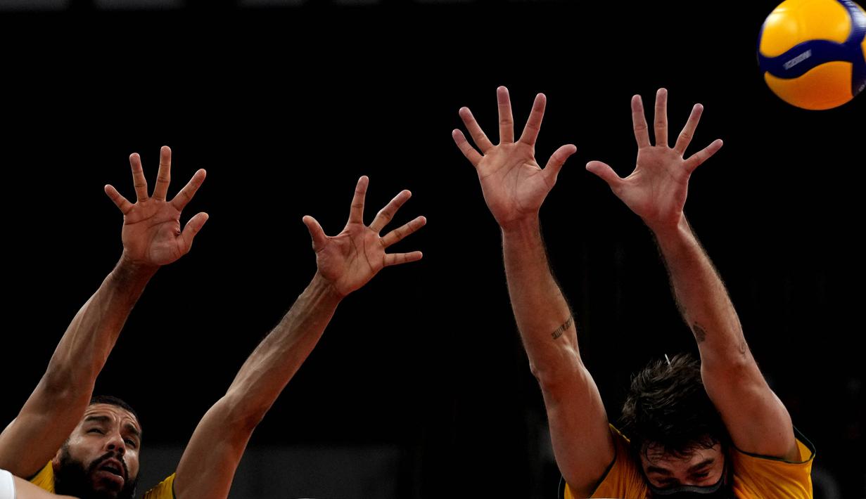 Pevoli Brasil, Lucas Saatkamp (kanan) melompat untuk memblokir bola saat babak penyisihan grup B bola voli putra Olimpiade Tokyo 2020 Brasil dan AS di Ariake Arena pada 1 Agustus 2021. Lucas menggunakan masker saat berlaga demi melindungi dirinya dan keluarganya dari Covid-19. (AP/Frank Augstein)