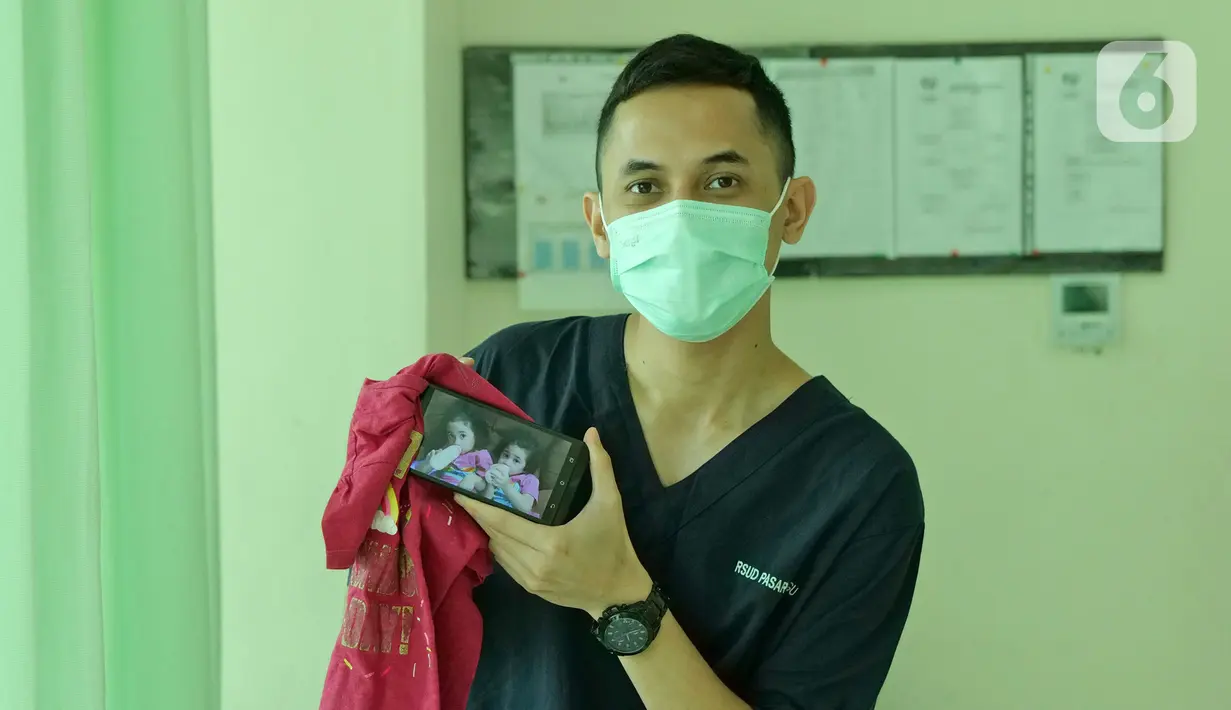 dr. Kevin William Hutomo (29) menunjukkan foto anaknya saat di RSUD Pasar Minggu, Jakarta, Jumat (22/5/2020). Kevin William Hutomo sudah 2 bulan tidak bertemu keluarga selama bertugas menjaga COVID -19 di RSUD Pasar Minggu. (Liputan6.com/Herman Zakharia)
