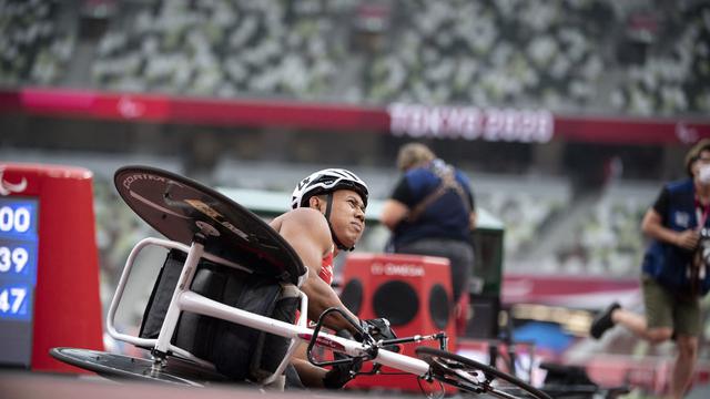 Atlet Indonesia, Jaenal Aripin, sempat terjatuh setelah melewati garis finis di atletik 100 meter putra T54 Paralimpiade Tokyo 2020, Rabu (1/9/2021). (AFP/Charly Triballeau)
