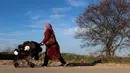 Seorang wanita migran mendorong kereta bayi dalam perjalanan menuju perbatasan Turki dengan Yunani di Pazarkule, Turki, Selasa (3/3/2020). (AP Photo/Darko Bandic)