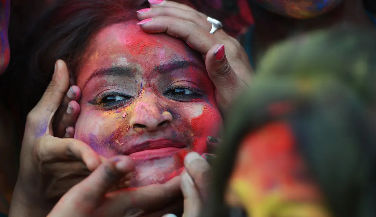 Wajah seorang perempuan yang dilumurkan bubuk warna selama mengikuti perayaan Holi di Kolkata, India (7/3). Selama perayaan tersebut, peserta saling melemparkan bubuk berwarna-warni atau saling menyiramkan air berwarna-warni. (AFP/Dibyangshu)