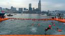 Perenang melompat ke dalam air saat mengikuti lomba renang tahunan di Pelabuhan Victoria, Hong Kong, Minggu (23/10/2022). (AP Photo/Anthony Kwan)
