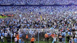 Para suporter tumpah ruah ke lapangan setelah berakhirnya laga antara Manchester City menghadapi Chelsea pada laga lanjutan pekan ke-37 Liga Inggris 2022/2023 di Stadion Etihad, Manchester, Minggu, (21/5/2023). Mereka larut dalam pesta gelar juara Man City. (Martin Rickett/PA via AP)