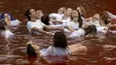 Orang-orang mandi dalam kolam warna merah untuk menandakan darah, selama protes terhadap invasi Rusia ke Ukraina di depan kedutaan besar Rusia di Vilnius, Lithuania, Kamis (7/4/2022). Protes tersebut menyoroti ancaman genosida dari operasi militer Rusia. (AP Photo/Mindaugas Kulbis)