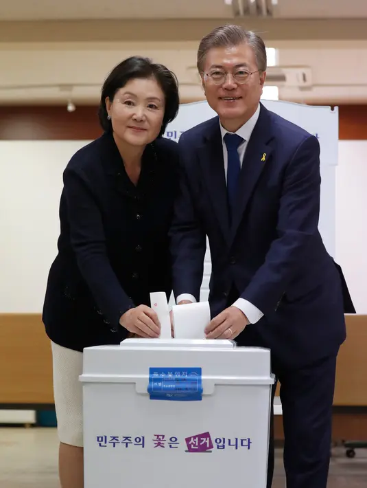Calon presiden Korsel dari Partai Demokrat Moon Jae-in bersama istrinya memasukkan kertas suara di sebuah TPS di Seoul, Selasa (9/5). Hari ini, warga Korsel mulai memilih presiden baru setelah pemakzulan Park Geun-hye. (Jeon Heon-kyun/Pool Photo via AP)