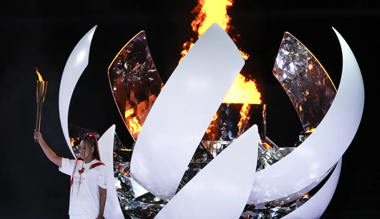 Atlet Jepang Naomi Osaka menyalakan baki api dari obor, dalam acara upacara pembukaan Olimpiade Tokyo 2020 di Olympic Stadium, di Tokyo, Jumat (23/7/2021). Upacara pembukaan Olimpiade Tokyo yang berlangsung dalam era pandemi digelar tanpa penonton. (AP Photo/Ashley Landis)