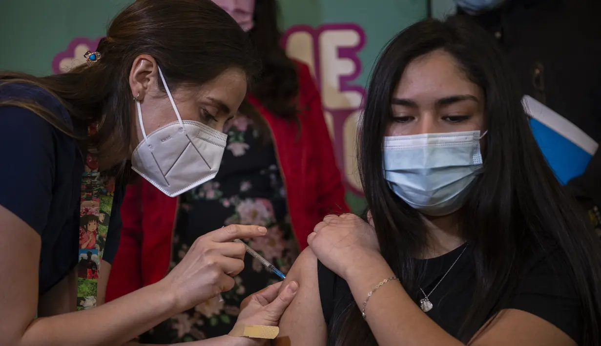 Petugas kesehatan menyuntikan vaksin COVID-19 Pfizer BioNTech kepada seorang anak di pusat vaksinasi di Santiago, Chile, Rabu (23/6/2021). Chile mulai memvaksinasi anak-anak dari usia 12 tahun, sebagai salah upaya untuk memutus rantai penyebaran infeksi virus Corona. (MARTIN BERNETTI/AFP)
