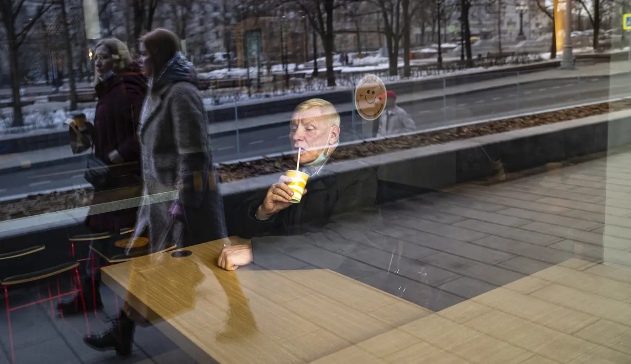 Seorang pria duduk di belakang jendela restoran McDonald's pada hari kerja terakhirnya di Pushkinskaya Square di Moskow, Rusia, Senin (14/3/2022). Gerai makanan cepat saji McDonald’s memutuskan setop beroperasi dari Rusia pasca invasi yang dilakukan Negeri Beruang Merah terhadap Ukraina. (AP Photo)