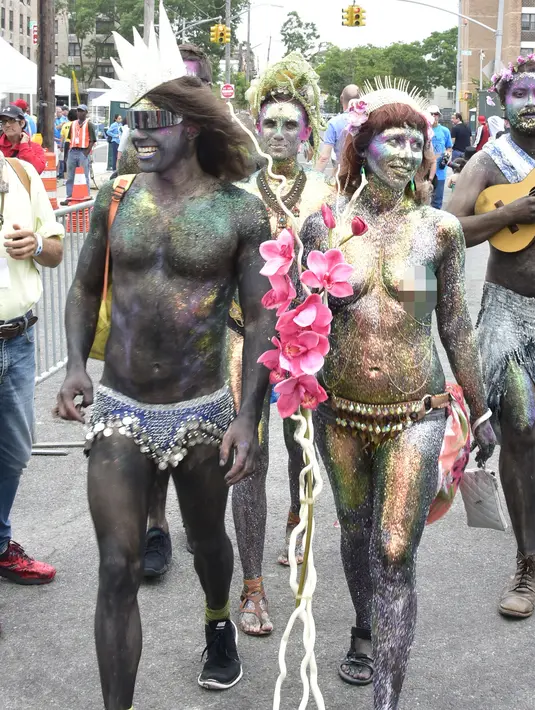 Pengunjung mewarnai tubuhnya saat mengikuti Parade Mermaid 2017 di Coney Island, New York City (17/6). Parade ini diikuti lebih dari 3000 orang peserta yang mengenakan busana bertema Mermaid.  (Eugene Gologursky/Getty Images for Stellar Productions/AFP)