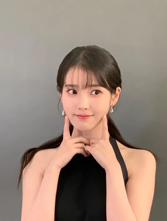 Sebelumnya, IU dikenal dengan rambut panjangnya yang indah dan berwarna hitam. Di foto ini, rambut panjang berponi IU ditata low-ponytail. [Foto: Instagram/dlwlrma]