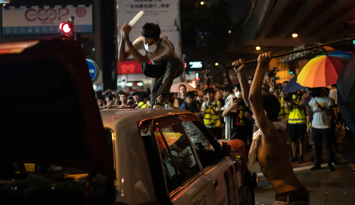 Demonstran menghancurkan sebuah taksi di Hong Kong, Minggu (29/9/2019). Demonstran di Hong Kong mengaku semakin bersemangat walau aparat melakukan tindak kekerasan. (AP Photo/Felipe Dana)