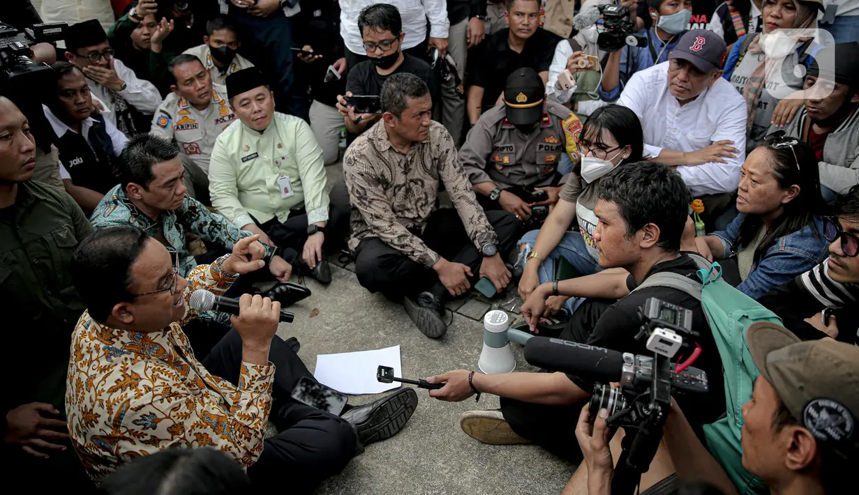 Gubernur DKI Jakarta Anies Baswedan berdiskusi dengan pendemo yang tengah melakukan orasi di depan gerbang Balai Kota DKI Jakarta, Jumat (14/10/2022). Dalam beberapa saat, peserta aksi duduk mendengarkan apa yang dikatakan Anies. (Liputan6.com/Faizal Fanani)