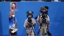 Manajer foto senam gymnastics, Rich Lam mengangkat tanda yang memberi isyarat kepada para atlet untuk mengenakan masker mereka saat seremoni penyerahan medali cabang senam nomor artistik putra Olimpiade Tokyo 2020 di Tokyo, Senin (26/7/2021). (AP Photo/Ashley Landis)