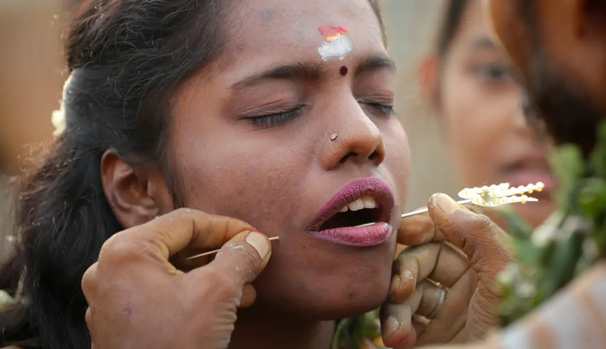 Seorang wanita menusuk pipinya dengan batang logam saat Festival Thaipusam di Gua Batu, Kuala Lumpur, Malaysia, Senin (21/1). Umat Hindu akan melakukan satu acara tertentu sebagai tanda kesyukuran bila hajat mereka terkabulkan. (AP Photo/ Vincent Thian)