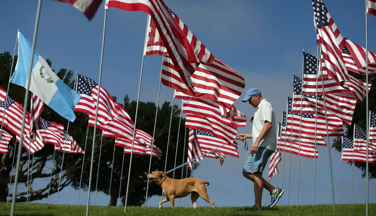 Seorang pria berjalan bersama anjing piaraan pada peringatan 15 tahun bagi para korban 11 September 2001 di Malibu, California, (11/09). Sebanyak 3.000 bendera AS dikibarkan, mewakili setiap nyawa yang hilang. (REUTERS/Lucy Nicholson)