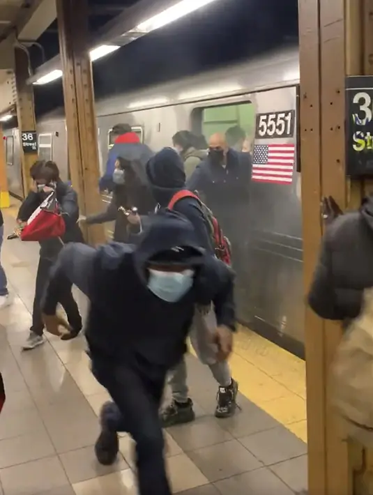 Penumpang berlari dari gerbong kereta bawah tanah di sebuah stasiun di wilayah Brooklyn, New York, Amerika Serikat, 12 April 2022. Seorang pria bersenjata memenuhi kereta bawah tanah pada jam sibuk dengan asap dan menembak beberapa orang. (Will B Wylde via AP)