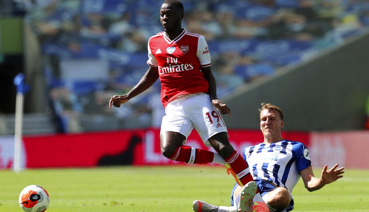 Pemain Brighton & Hove Albion, Dan Burn, berebut bola dengan pemain Arsenal, Nicolas Pepe, pada laga Premier League di Stadion Falmer, Sabtu (20/6/2020). Arsenal kalah 1-2. (AP/Gareth Fuller)