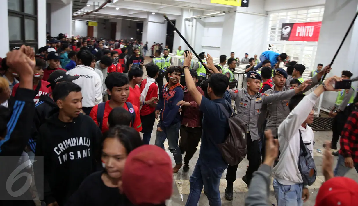 Petugas kepolisian berusaha menenangkan suporter yang memaksa masuk ke dalam tribun saat berlangsungnya leg pertama final Piala AFF 2016 antara Indonesia melawan Thailand di Stadion Pakansari, Bogor, Rabu (14/12). (Liputan6.com/Johan Tallo)