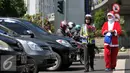 Menyambut Hari Natal 2015, anggota Kepolisian Polres Jakarta Barat kenakan topi Sinterklas dan bagikan bunga serta masker kepada pengguna jalan di kawasan Tomang, Jakarta, Rabu (23/12). (Liputan6.com/Yoppy Renato)