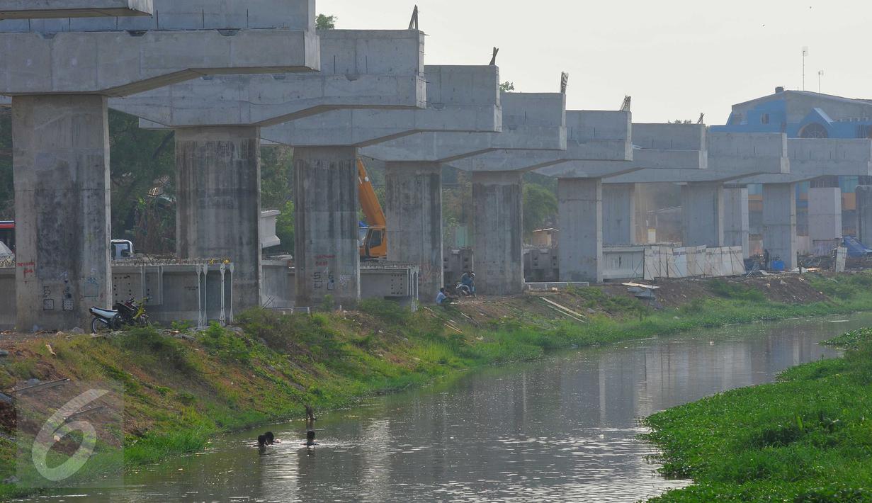 Warga beraktivitas di sekitar proyek pembangunan jalan tol Bekasi-Cawang-Kampung Melayu (Becakayu), Jakarta, Jumat (6/11). Proyek yang sempat terbengkalai selama 17 tahun tersebut kini diakuisisi dan dikerjakan oleh BUMN. (Liputan6.com/Gempur M Surya)