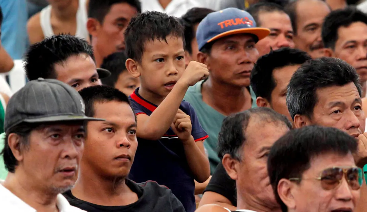 Seorang bocah Filipina menirukan gerakan Manny Pacquiao sambil menonton siaran langsung pertandingan bersama para orang tua di Manila (13/4/2014). (REUTERS/Romeo Ranoco)