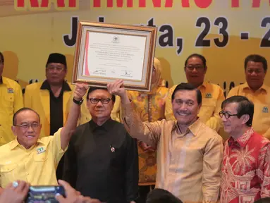 Ketua umum Partai Golkar, Aburizal Bakrie dengan Menkopolhukam Luhut Panjaitan mengangkat pigura berisi hasil keputusan Rapimnas Partai Golkar 2016, Jakarta, Senin (25/1/2016). (Liputan6.com/Angga Yuniar)