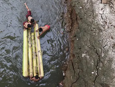 Anak-anak berenang menggunakan batang pohon pisang di bantaran Sungai Ciliwung, Jakarta, Selasa (15/5). Kurangnya pengawasan menyebabkan anak-anak tersebut bermain tidak pada tempatnya. (Liputan6.com/Immanuel Antonius)