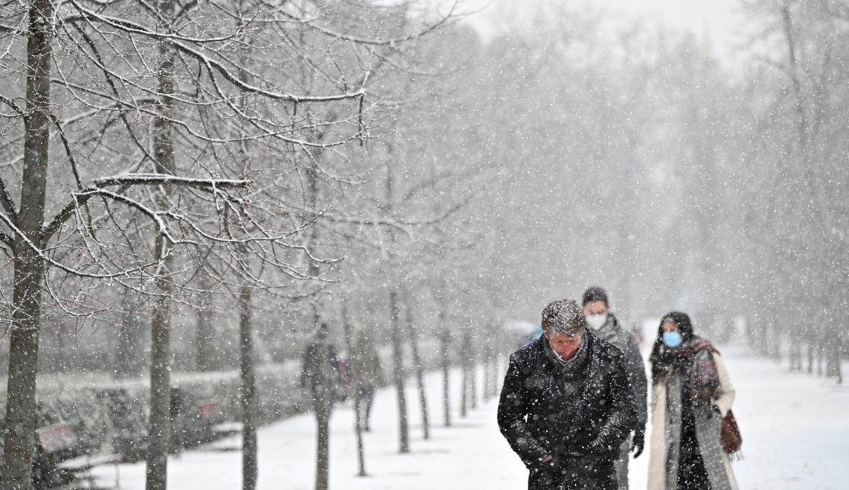 Orang berjalan saat salju turun di Madrid (7/1/2021). Badan cuaca Aemet mengatakan bahwa Kepulauan Canary sudah merasakan dampak Filomena melalui angin kencang, laut yang ganas dan curah hujan yang tinggi. (AFP/Gabriel Bouys)