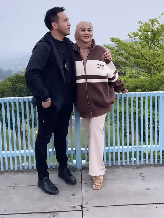 <p>Jenita pun semakin lengket dengan sang suami, ia tampil serba coklat dengan jaket dan kerudungnya. (@jenitajanet)</p>