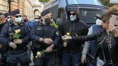 Demonstran membawa bunga untuk petugas polisi selama aksi protes di Circus Maximus Roma, Jumat (15/10/2021). Protes tersebut karena aturan yang mengharuskan seluruh pekerja di Italia menunjukkan kartu kesehatan covid-19 untuk memasuki tempat kerja mereka. (AP Photo/Gregorio Borgia)