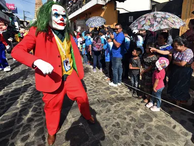 Anggota Saturno Club dengan kostum Joker melakukan parade Dance of Costumes tahunan di sepanjang jalan kota Sumpango, Guatemala, Senin (30/12/2019). Parade kostum yang menampilkan karakter televisi dan film ini untuk memeriahkan malam pergantian tahun. (ORLANDO ESTRADA/AFP)