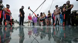 Seorang pria memukulkan palu untuk mengukur kekuatan jembatan di Provinsi Hunan, Cina, (25/6). Ini dilakukan untuk mengetahui keamanan yang dimiliki oleh jembatan dari kaca ini. (REUTERS / Jimmy Guan)