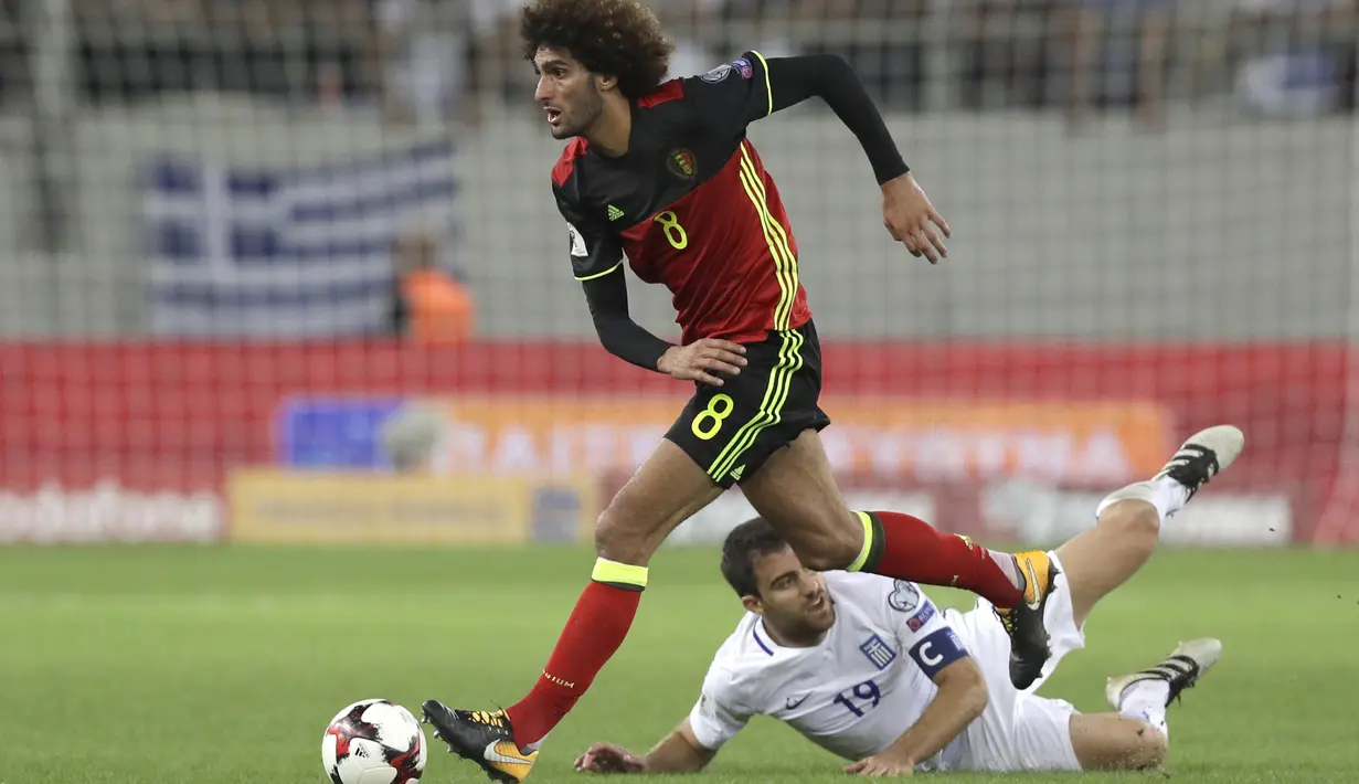 Aksi Marouane Fellaini (kiri) melewati adangan pemain Yunani, Sokratis Papastathopoulos pada laga grup H kualifikasi Piala Dunia 2018 di Georgios Karaiskakis Stadium, Piraeus port, Yunani, (3/9/2017). Belgia menang 2-1. (AP/Thanassis Stavrakis)