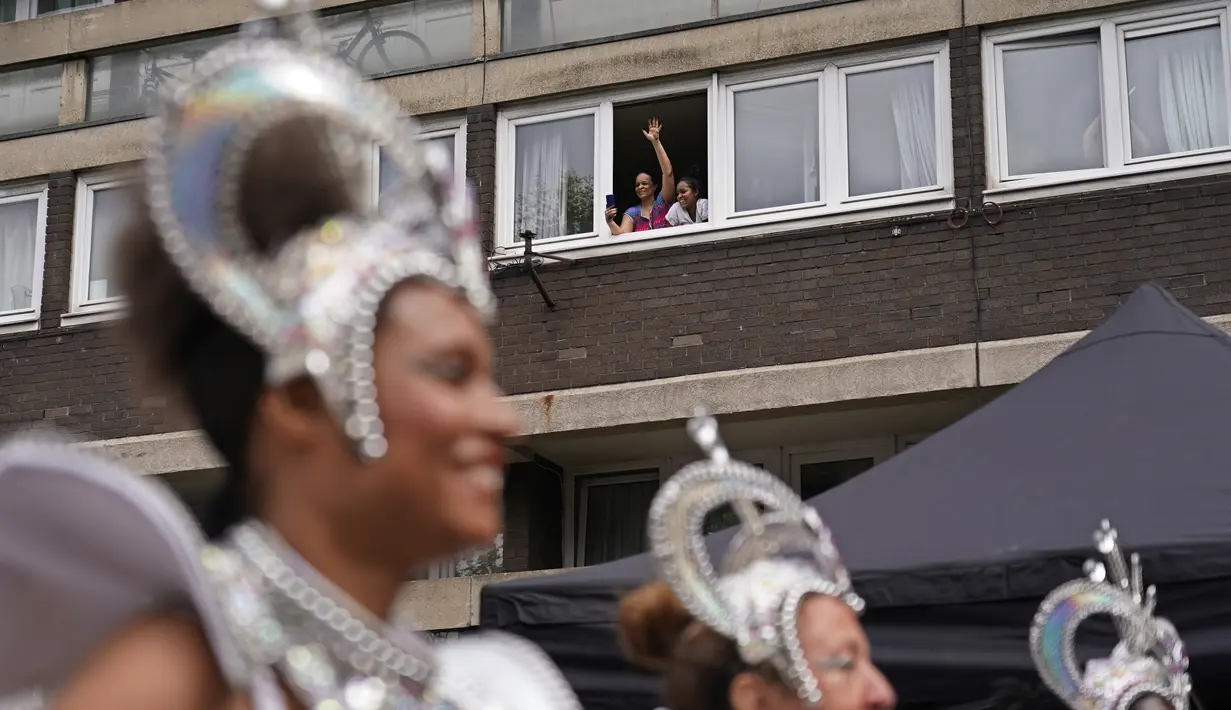 Seorang wanita melambai dan merekam dengan ponselnya dari jendela saat para penampil mengambil bagian dalam Karnaval Notting Hill tahunan di London barat, Senin (29/8/2022). Karnaval yang kembali ke jalanan untuk pertama kalinya dalam dua tahun, setelah digagalkan oleh pandemi, adalah salah satu perayaan festival terbesar dari jenisnya di Eropa. (AP Photo/Alberto Pezzali)
