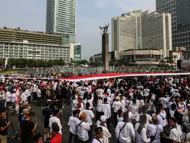 Sejumlah peserta membentangkan Bendera Merah Putih di kawasan Thamrin, Jakarta, Minggu (28/8/2022). Sebanyak 50.000 orang membentangkan bendera merah putih sepanjang 1.700 meter dari kawasan Monas hingga Bundaran Hotel Indonesia dalam rangka memperingati HUT ke-77 Kemerdekaan Republik Indonesia bertemakan 'Pulih Lebih Cepat, Bangkit Lebih Kuat. (Liputan6.com/Johan Tallo)