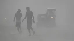 Penduduk berjalan saat gunung berapi Taal memuntahkan abu vulkanik di Lemery, provinsi Batangas, Filipina, Senin (13/11/2020). Erupsi gunung Taal memaksa puluhan ribu orang mengungsi serta membuat sekolah-sekolah dan toko di Manila tutup. (AP/Aaron Favila)