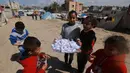 Seorang gadis muda Palestina menjual permen kepada anak-anak di sebuah kamp di Rafah, Jalur Gaza selatan pada 7 Maret 2024. Perang dan pembatasan oleh Israel membuat warga Gaza dihantui sejumlah krisis akibat kelangkaan makanan, air, obat-obatan serta potensi penyebaran penyakit imbas lemahnya layanan medis. (MOHAMMED ABED / AFP)