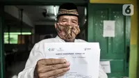 Warga lansia menunjukkan surat bukti vaksin COVID-19 di SDN 05 Penggilingan, Jakarta, Kamis (25/2/2021). Pemerintah berharap vaksinasi tahap kedua terhadap lansia selesai pada Mei 2021 guna menekan penyebaran COVID-19. (merdeka.com/Iqbal S. Nugroho)