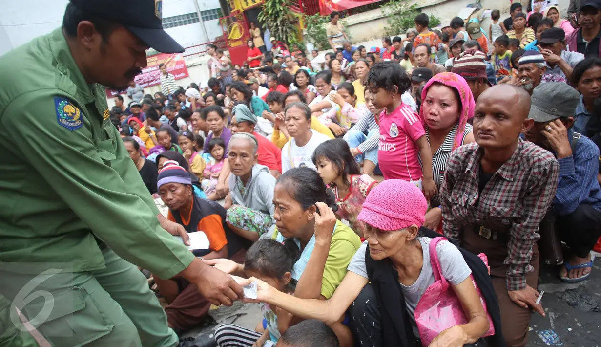 Petugas keamanan membagikan uang angpau kepada para pengemis di selasar Vihara Dharma Bahkti, Petak Sembilan, Jakarta Barat, Sabtu (28/1). Mereka mengantre untuk mendapatkan uang angpau dari warga keturunan Tionghoa. (Liputan6.com/Imamnuel Antonius)