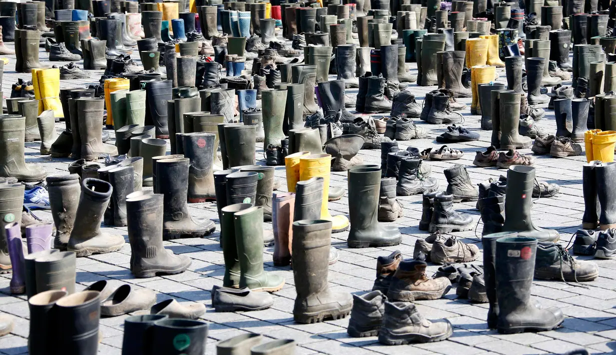 Ratusan pasang sepatu boots memenuhi depan gerbang Brandenburg, Berlin saat aksi protes oleh peternak sapi perah di Jerman, Senin (30/5). Mereka menuntut harga produk susu yang lebih adil bagi para peternak. (REUTERS/Fabrizio Bensch)